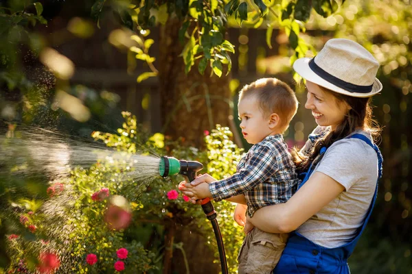 Mulher jardineiro com filho rega jardim — Fotografia de Stock