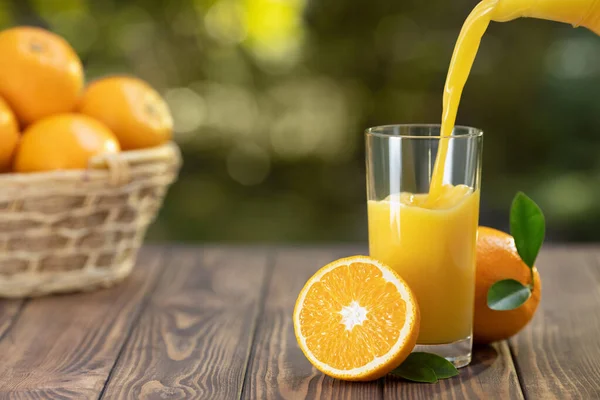 Apelsinjuice som hälls i glas — Stockfoto