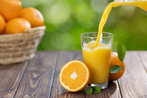 Apelsinjuice som hälls i glas — Stockfoto