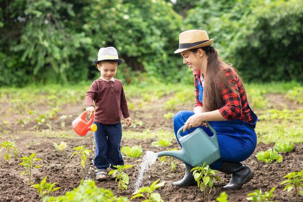 woman gardener with son watering garden