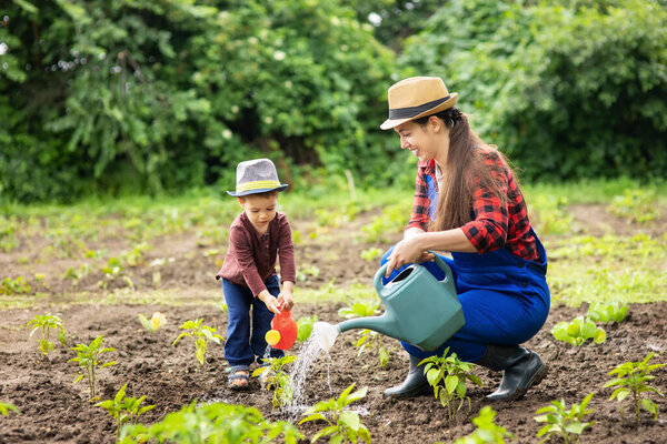 woman gardener with son watering garden
