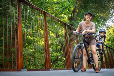 Anne ve oğlu bisiklete biniyor.