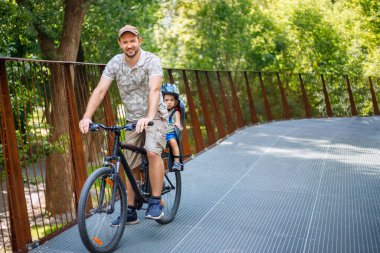 Baba oğul bisiklete biniyor.