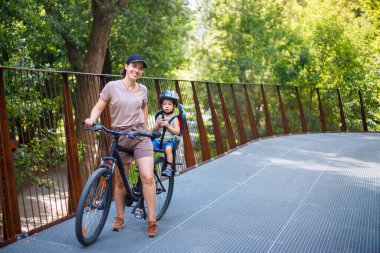 Anne ve oğlu bisiklete biniyor.