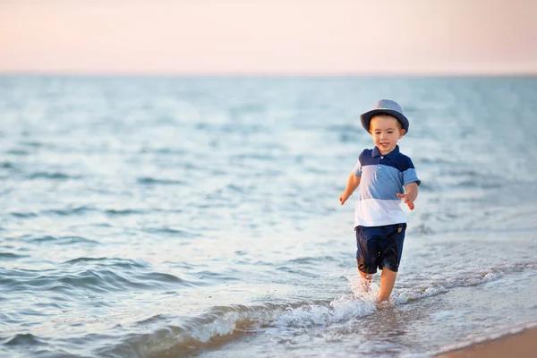 Küçük çocuk deniz sahilinde koşuyor.