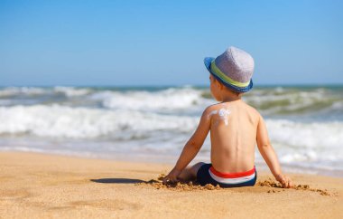 Omzunda güneş kremi olan küçük çocuk.