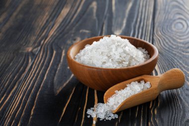 Kasede beyaz deniz tuzu ve koyu ahşap masada kepçe.