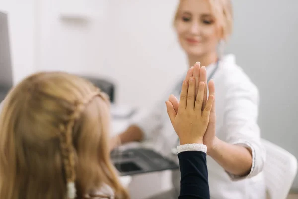 Paediatrician explains results of examination to kid girl in a friendly manner