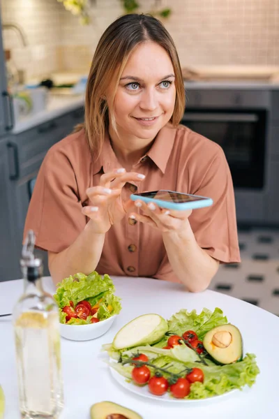 Food blogger uses smartphone for taking photos of vegetables.