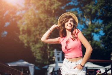 Uzun kıvırcık saçları sahilde eğleniyor, dans ve gülümseyen, tatil ruh kameraya gülümseyen etkili kız closeup portresi. Şapkalı güzel gülen kız.