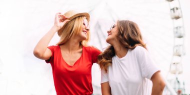 En iyi arkadaşım dönme eğleniyor, birlikte, delirmek şapkalar ve yansıtılmış güneş gözlüğü, kentin parlak şaşırtıcı görünümünde akşam güneş ışığı renkler.