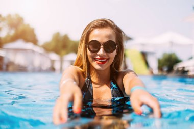 Şık kız eğleniyor havuzu, modaya uygun kıyafet ve güneş gözlüğü, Lüks Havuz görünüm şaşırtıcı vibes, seyahat olumlu yaz portresi. Seksi mükemmel fit vücut kadın. Kopyalama, metin için boş yer