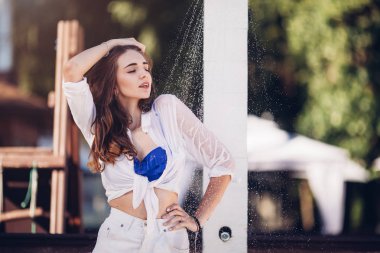 Isı ve ferahlık kavramı. Su üzerinde çekici kadın düşüyor düşüyor. Genç güzel esmer kız alma duş plajda Yüzme sonra. Bikinili seksi Bayan duş sıcak güneşli günde sahiptir.