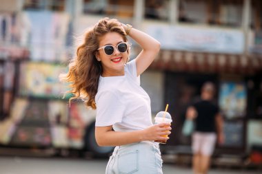 Harika beyaz kadın model parlak makyaj iyi günde enerji ifade ile portresi. Sevimli kız kısa denim şort ve parlak t-shirt, Festival Eğlence parkı olan joying sunglassesen. kokteyl tutar