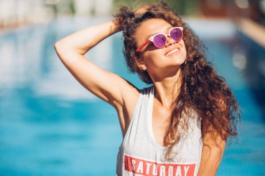 Genç, şehvetli, güzel bir kadın sahilde poz veriyor modern hippi kıyafetleri, lüks tatil kıyafetleri, sıcak yaz moda aksesuarları, şık güneş gözlükleri..