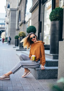 genç güzel esmer kahve yürüme city.leather ceket, kentsel sırt çantası, parlak kırmızı dudaklar içme