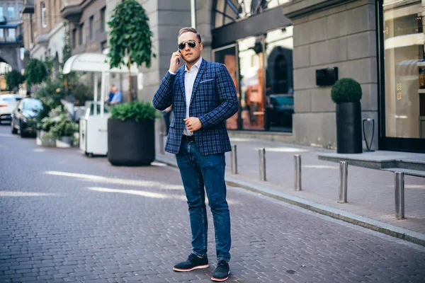 Retrato de un joven guapo, modelo de moda, con gafas de sol teñidas en el fondo urbano — Foto de Stock