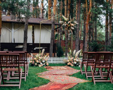 Düğün merasiminin yapılacağı yer bir çam ormanının pitoresk bir yerinde. Kırsal tarzda. Kemer güzel çiçek buketleriyle süslenmiş..