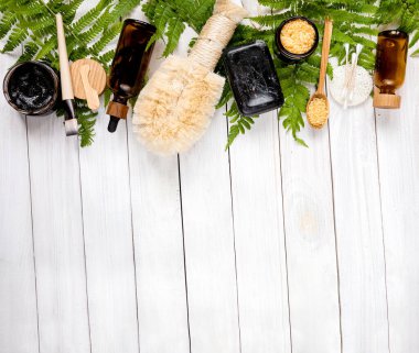 Çeşitli çevre dostu kozmetik ürünlere sahip organik spa konsepti. Losyon, vücut yağı, maske, banyo tuzu, el yapımı siyah sabun ve bambu fırçası ile cilt bakım ürünleri. Metnin için boşluk kopyala