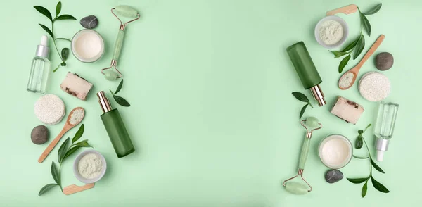 Yeşil spa ya da sağlıklı yaşam çerçevesi. Yapraklar, gövde ve yüz bakım araçları ve aksesuarlar yeşil arka planda, üst görünüm. Çeşitli çevre dostu kozmetik ve cilt bakım ürünlerine sahip güzellik geçmişi. Metinler için alan.