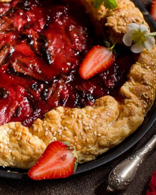 Karanlık bir arka plan üzerinde çilek ile tart. Yeşil çilek yaprakları, taze çilek çilek. Kırmızı koşucu. Kırmızı pasta kabuk. Seçici odak. Karanlık fotoğraf.