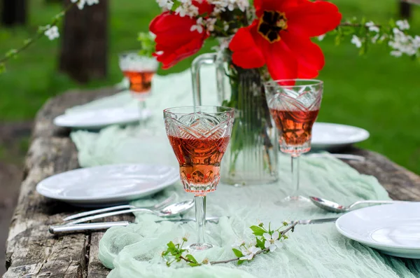 庭の美しい背景お祝いテーブル 古い木製のテーブル 桜の花 ワインのグラス 柔らかい緑のランナー 選択と集中 背景をぼかした写真 — ストック写真