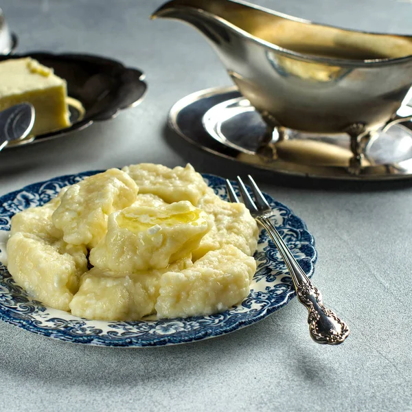 Hot lazy dumplings with butter. Curd dessert. Traditional Russian dish. The dumplings on the plate. Silverware. Selective focus. Close up.