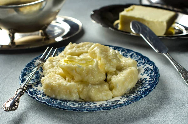 Hot lazy dumplings with butter. Curd dessert. Traditional Russian dish. The dumplings on the plate. Silverware. Selective focus. Close up.