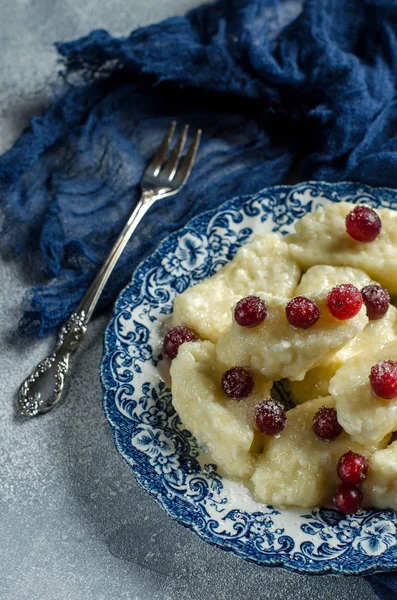 Lazy dumplings with cottage cheese and red berries on a plate. Traditional Russian cuisine. Blue runner. Selective focus.