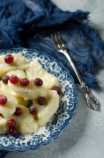 Lazy dumplings with cottage cheese and red berries on a plate. Traditional Russian cuisine. Blue runner. Selective focus.