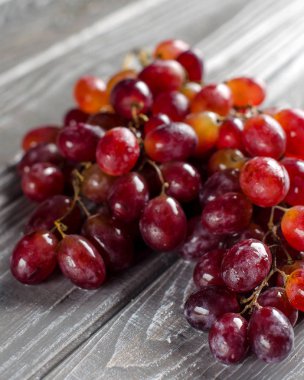 Ahşap bir masa üzerinde pembe üzüm demet. Hasat. Yakın çekim. Su damlacığı. Seçici odak.