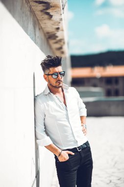 Başarılı bir genç iş adamı portresi duvara yaslanmış giyinmiş. Şık genç adam kavramı