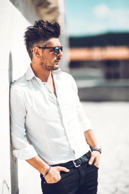 Başarılı bir genç iş adamı portresi duvara yaslanmış giyinmiş. Şık genç adam kavramı