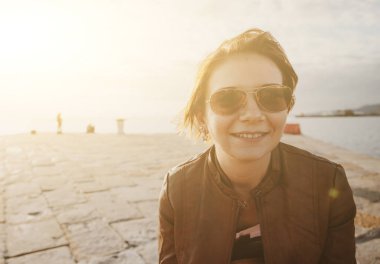 Deniz ve gün batımı arka plan ile sevimli genç gülümseyen kız portresi