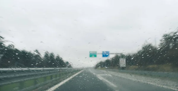 Driving in the heavy rain and slippery road. Abstract blurred bad weather on the highway.Car point of view.