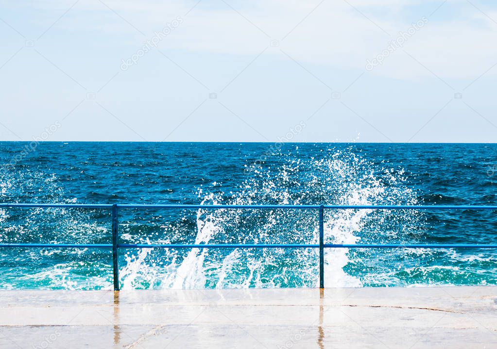 Huge stormy sea waves splash on cement pier.
