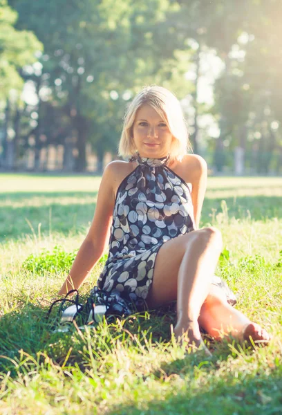 庭の芝生に座ってのファッショナブルな若い官能的なブロンドの女性の肖像画 — ストック写真