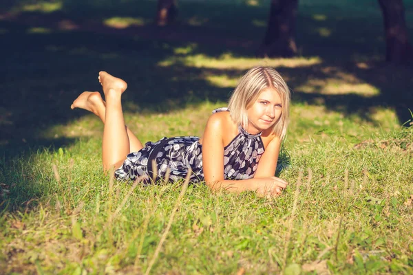 时尚年轻的感性金发碧眼的女人的肖像在花园里坐在草地上 — 图库照片