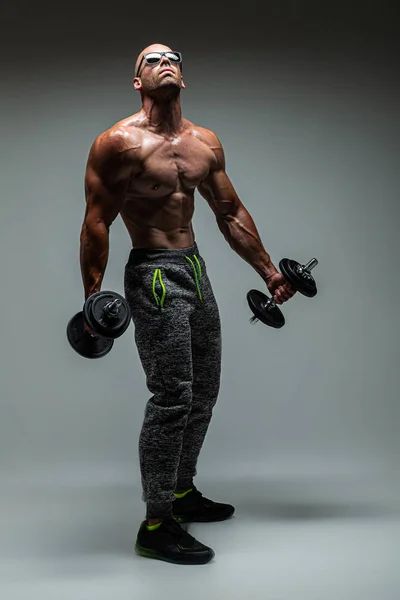 Muskulöser Mann Mit Sonnenbrille Posiert Mit Hanteln Auf Grauem Hintergrund — Stockfoto