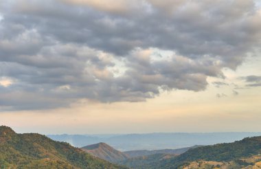 Bulutlu gün batımı gökyüzü ile dağ ve orman manzarası