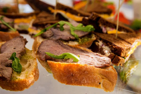Бутерброды с мясом и соусом песто на банкетном столе — стоковое фото