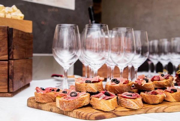 Snacks with ham on the banquet table and glasses of wine — Stock Photo, Image