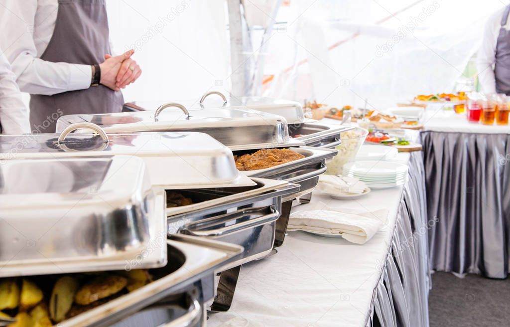 the waiter of the catering service serves a buffet table