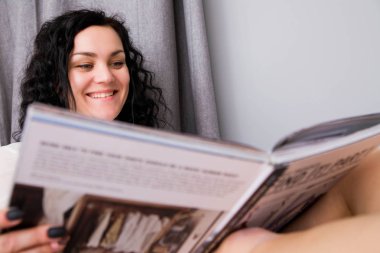 güzel genç kadın fotoğrafı evde bir dergi okuma arkasında duruyor