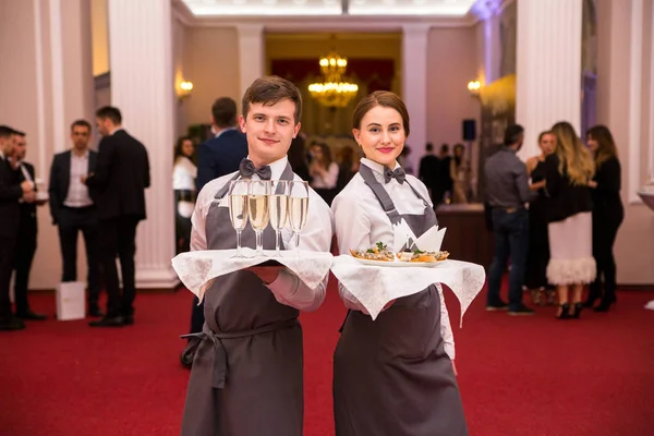 Minsk, Beyaz Rusya - 7 Haziran 2018. Garsonlar - bir adam ve bir kız gözlük elinde bir tepsi ile