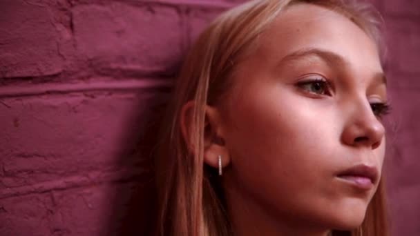 Dívka stojí u cihlové zdi a je smutné — Stock video
