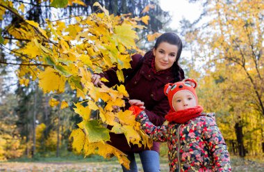 Onun kızı sonbahar yaprakları anne gösterir fotoğraf