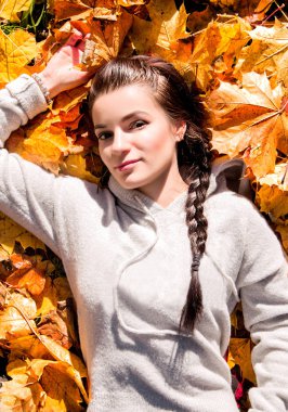 Kızın fotoğrafı sonbahar yaprakları üzerinde yatıyor