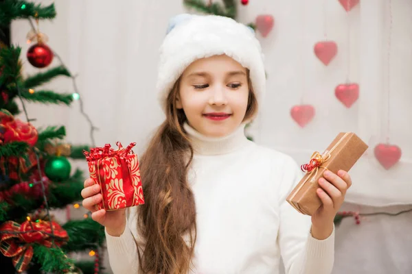 Κορίτσι με καπέλο Σάντα και χριστουγεννιάτικα δώρα στα χέρια τους — Φωτογραφία Αρχείου
