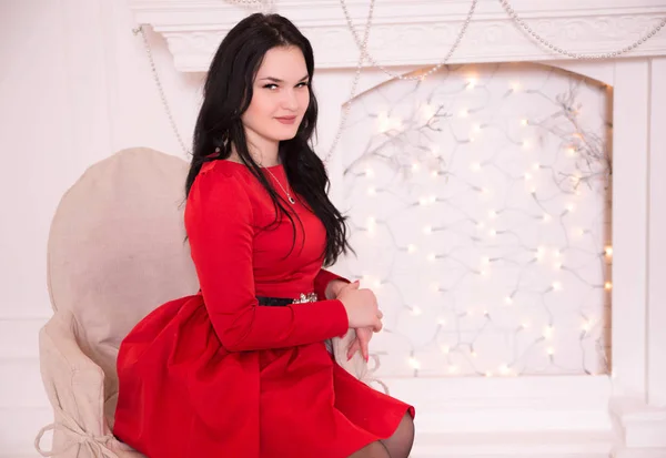Dívka v červených šatech na pozadí vánočních světel — Stock fotografie